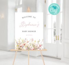 a welcome sign for a baby shower is displayed in front of a white room with an open door