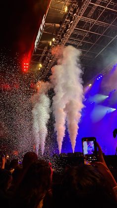 people are taking pictures with their cell phones as fireworks go off in the air at an outdoor concert