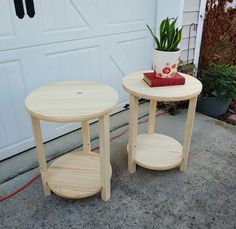 two wooden tables sitting next to each other near a garage door and potted plant