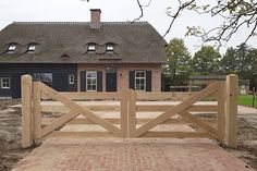 a house with a brick walkway leading to it and a wooden gate in front of it