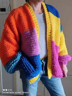 a woman wearing a multicolored knitted cardigan standing in front of a door