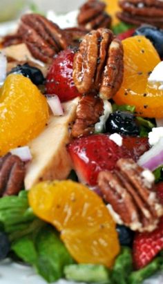 a salad with oranges, strawberries, pecans and blue cheese on it