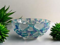 a glass bowl sitting on top of a table next to two small green planters