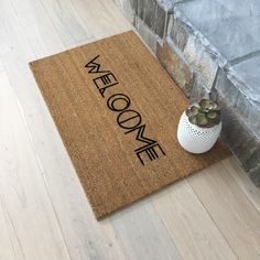 a welcome mat sitting on the floor next to a potted succulent plant