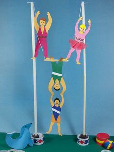 some paper dolls are standing on top of the pole with their hands in the air