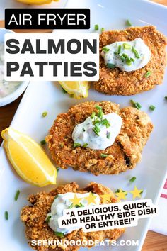 three fried salmon patties on a white plate with lemon wedges and sour cream