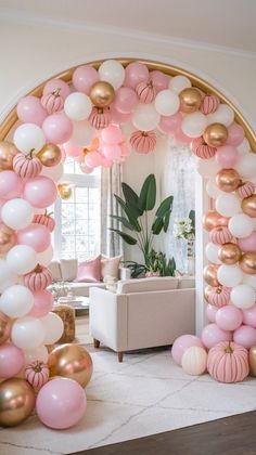 an arch made out of balloons and other decorations in a living room with a couch