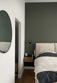 a bed sitting next to a wall with a round mirror on it's side