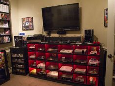 a large television mounted on top of a wooden shelf filled with video game controllers and games