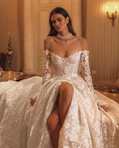 a woman in a wedding dress sitting on a bed with her legs crossed and wearing high heels