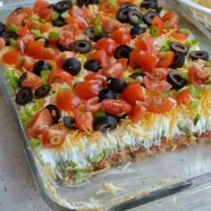 a casserole dish with black olives, tomatoes and other toppings on it