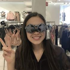 a woman is holding up her peace sign and wearing a bow tie on top of her blindfold