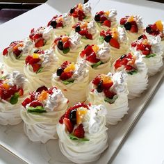 a white plate topped with lots of cupcakes covered in whipped cream and fruit