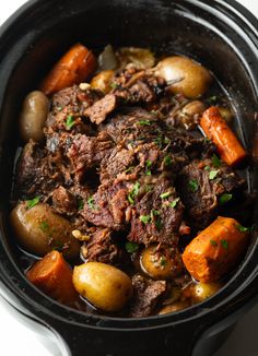 pot roast with carrots, potatoes and parsley in a black crockpot