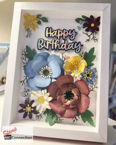 a birthday card with flowers and the words happy birthday written on it in white frame