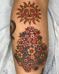 a sun and flowers tattoo on the leg