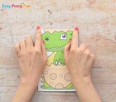 two hands holding an easy peasy fun book with a green dinosaur on it,