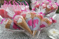 some ice cream cones with pink and silver designs on them are sitting on a table