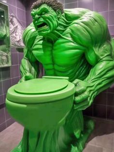 a green toilet sitting in the middle of a bathroom with a giant hulk statue on it's side