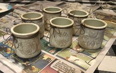 six ceramic jars with designs on them sitting on a table