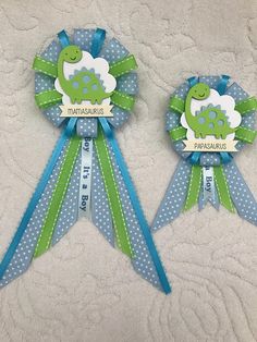 two green and blue ribbon award ribbons on a white surface with polka dots, one has a giraffe in the center