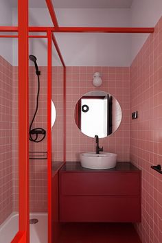 a bathroom with pink and red tiles on the walls