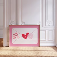 an envelope with a heart drawn on it in front of a white wall and wooden floor