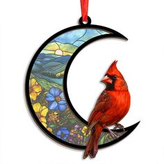 a stained glass ornament with a cardinal perched on the moon