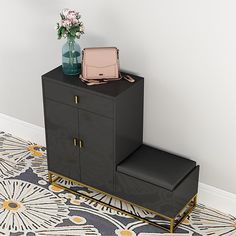 a black cabinet with a pink purse on top and a flower vase next to it