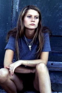 a woman sitting on the ground in front of a blue door with her legs crossed