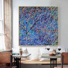 a painting hanging on the wall in a dining room next to two chairs and a table