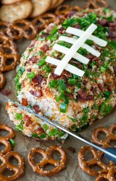 a football covered in cheese and bacon with pretzels on the side