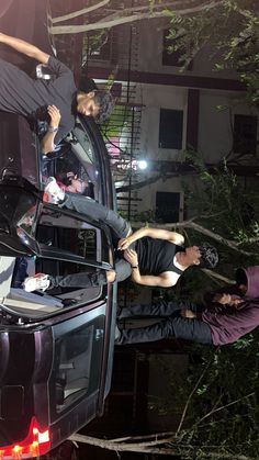 two men standing on the back of a truck with their hands in the open trunk