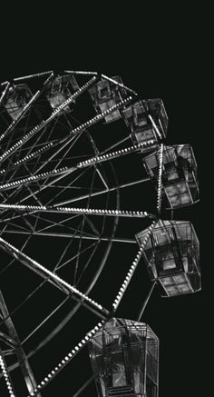 an old ferris wheel in black and white with lights on it's wheels is seen against a dark background