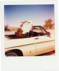 two people sitting in the back of a convertible car