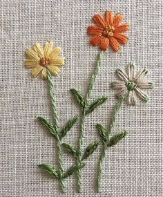 three different colored flowers sitting on top of a table