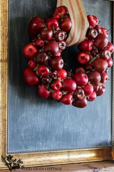 an apple wreath hangs on the wall in front of a chalkboard with a burlock