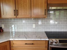 a kitchen with wooden cabinets and white marble counter tops, stainless steel oven and range