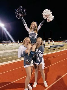 three cheerleaders posing for a photo on the sidelines