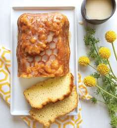 a white plate topped with bread next to a cup of coffee and some yellow flowers