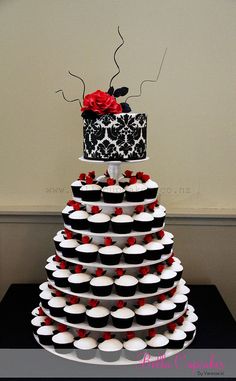 a tiered cake with cupcakes and a red rose on top is decorated in black and white