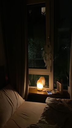 a bed sitting next to a window with a lamp on it's headboard