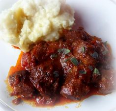 a white plate topped with meat and mashed potatoes