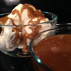 two bowls filled with ice cream and caramel sauce on top of a black table