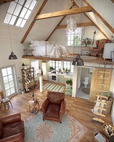 an aerial view of a living room and kitchen area with wood floors, exposed beams, vaulted ceiling, and leather chairs