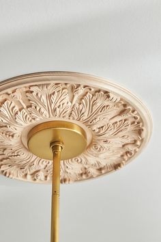 an ornate ceiling light fixture with a gold colored metal rod and leaf design on it