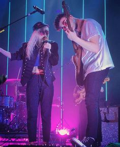 two people on stage with guitars and microphones