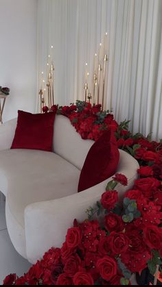 a white couch surrounded by red roses and candles