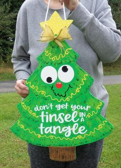 a woman is holding up a sign that says don't be your tinsel in a tangle