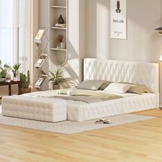 a white bed sitting on top of a hard wood floor next to a book shelf